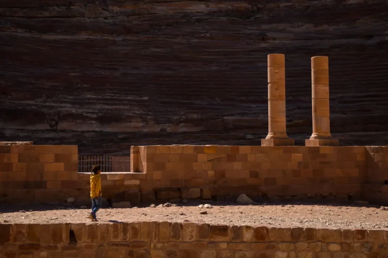 Child wearing a yellow jumper, walking across Jordan's ancient grounds