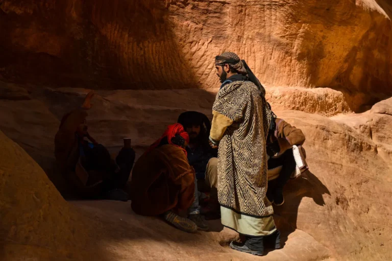 Group of men sitting in a small cave made of sandstone